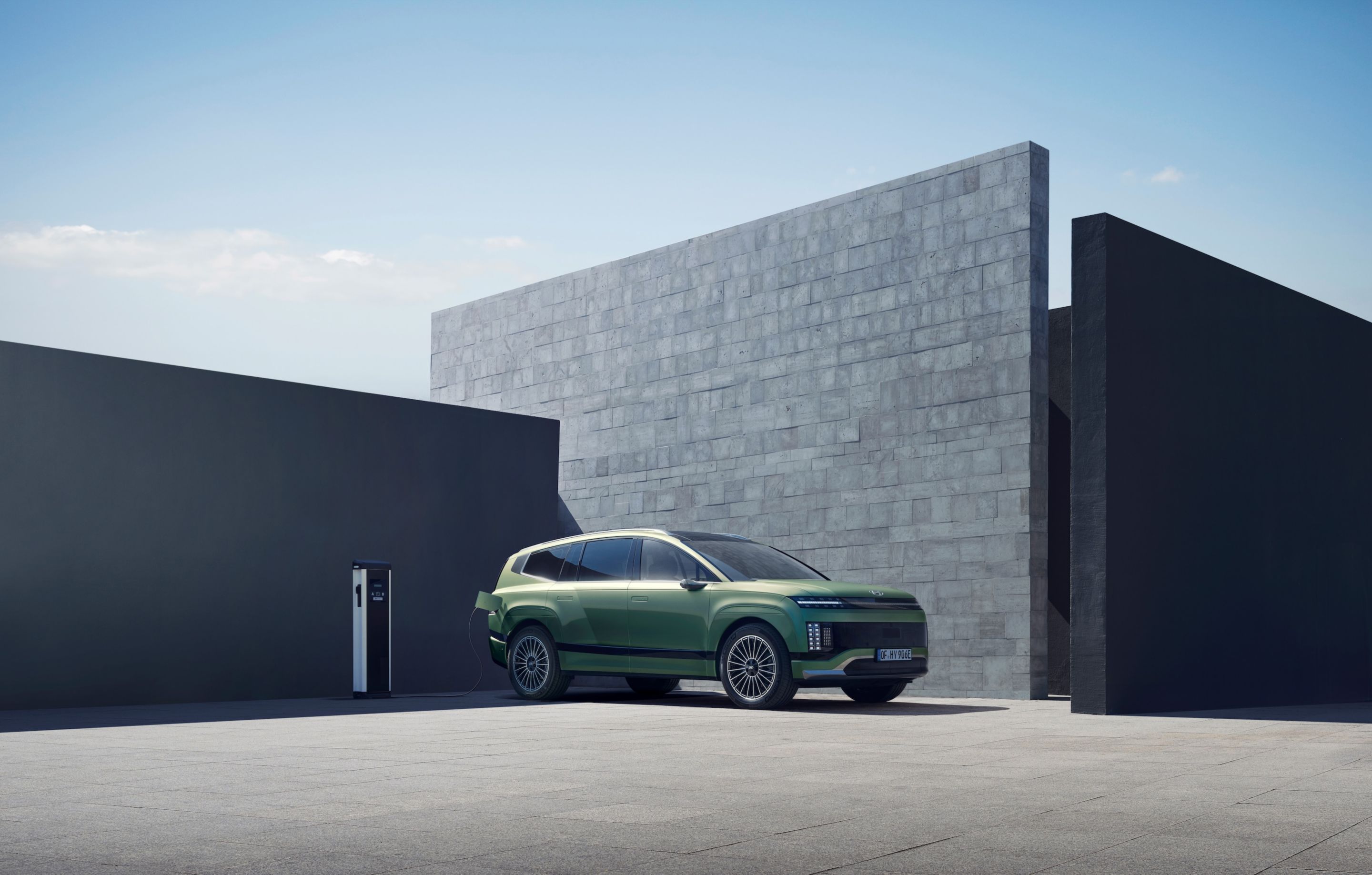SUV eléctrico Hyundai IONIQ 9 enchufado cargando frente a una casa.
