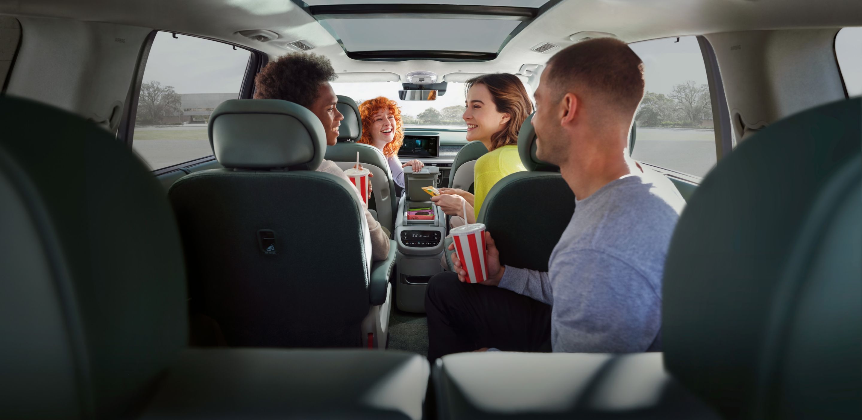 Cuatro personas en el interior del Hyundai IONIQ 9 compartiendo snacks y bebidas.