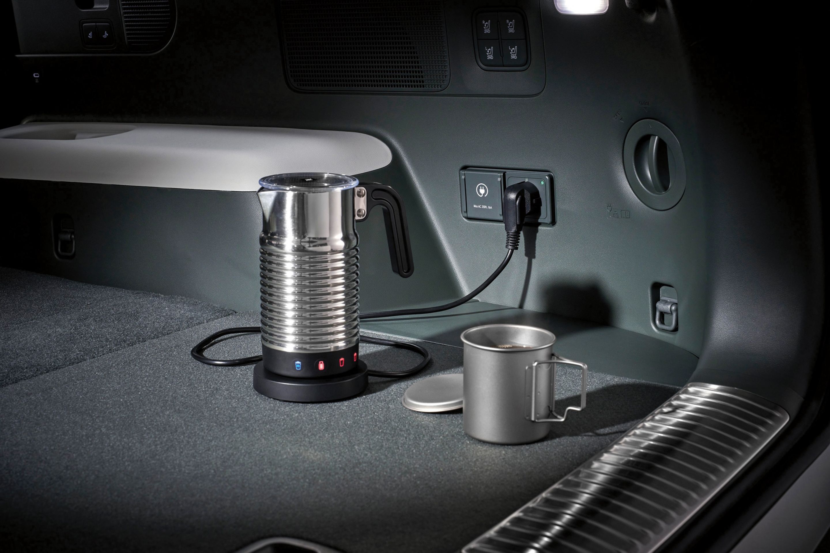 Toma de corriente interior en el baúl del SUV eléctrico Hyundai IONIQ 9 alimentando una cafetera.